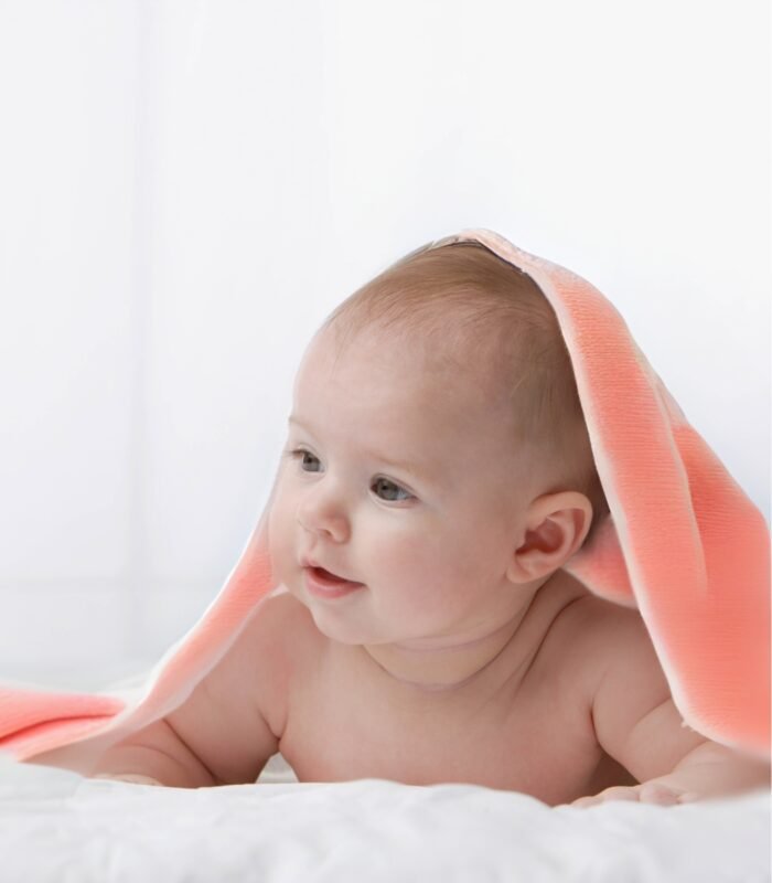 baby on bed with blanket peach